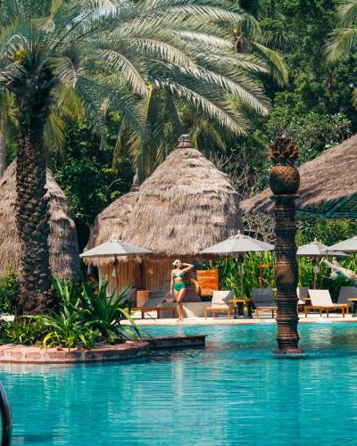 a woman walking by a swimming pool at a resort at Anantara Hua Hin Resort in Hua Hin