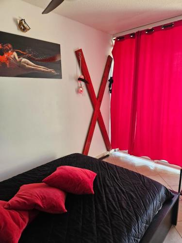 - une chambre avec des rideaux rouges et un lit avec des oreillers rouges dans l'établissement Studio village naturiste vue sur port nature 7, au Cap d'Agde