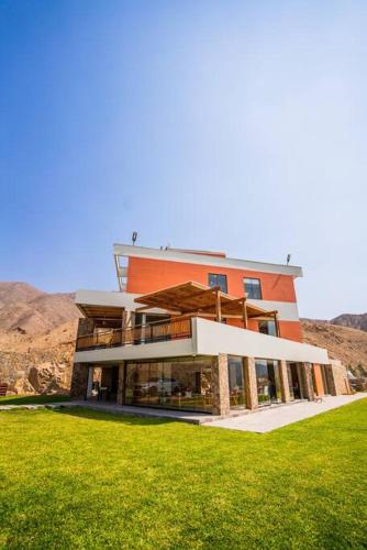 a large orange building with a green lawn in front of it at Casa Dama in Cieneguilla