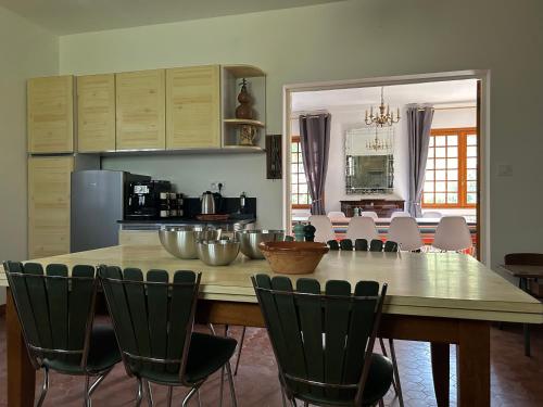 une cuisine avec une grande table et des chaises en bois dans l'établissement Gîte les Mercieres la Villa Maison campagne grands espaces oasis de nature, convivialité, détente 5 Chambres piscine chauffée Wifi piano billard, à Pexiora