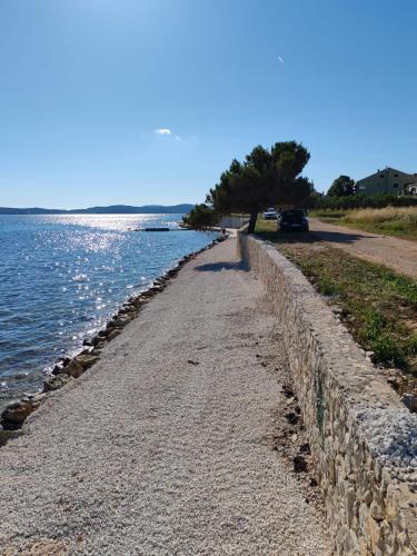 a stone wall next to a body of water at Seaside Serenity "Earth" with pool, 150m from sea in Sukošan