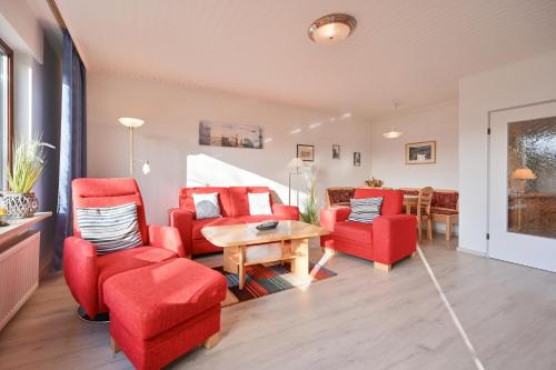 ein Wohnzimmer mit roten Stühlen und einem Tisch in der Unterkunft Bungalow Vaupel in Kellenhusen