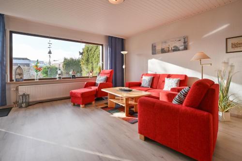ein Wohnzimmer mit roten Möbeln und einem großen Fenster in der Unterkunft Bungalow Vaupel in Kellenhusen