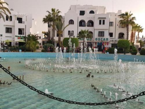 a fountain in a pool with people in the water at Sousse Marina Kantaoui l'expérience côtière in Port El Kantaoui