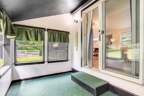 an empty room with windows and a green bench at Peaceful Brookside Getaway about 10 Mi to Okemo Slopes! in Chester