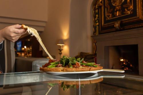 a person is holding a piece of pizza on a table at Presidente InterContinental Puebla by IHG in Puebla
