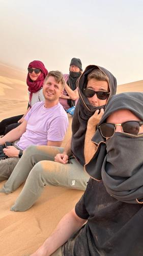 a group of people sitting in the desert at Riad Al-Badouin in Mhamid
