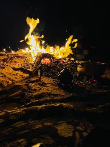 a fire is burning in the sand at night at Riad Al-Badouin in Mhamid
