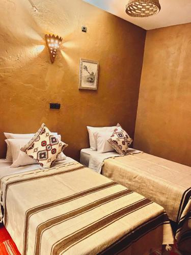 a room with two beds in a room at Riad Al-Badouin in Mhamid