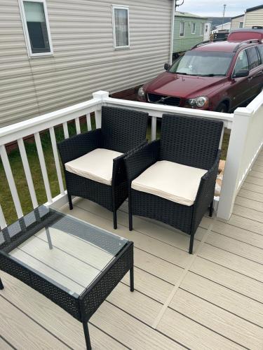 two wicker chairs and a table on a deck at 23 Chestnut Grove in Kirkcolm