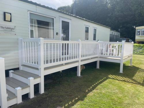 a white house with a porch and a dog under it at 23 Chestnut Grove in Kirkcolm