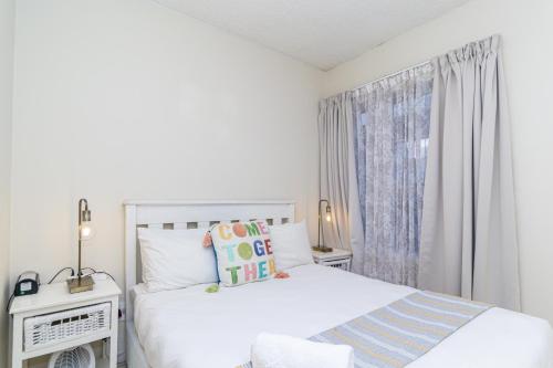 a white bedroom with two beds and a window at Modern Seaview Apartment in Summerstrand