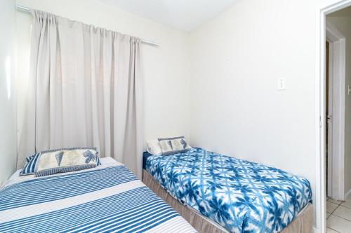 two beds in a room with white walls at Modern Seaview Apartment in Summerstrand