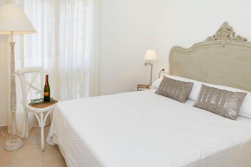 Dormitorio blanco con cama blanca y botella de vino en Villa Sa Calma Beach Sa Riera, en Begur
