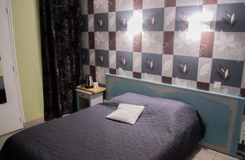 - une chambre dotée d'un lit bleu avec un oreiller blanc dans l'établissement Le relais du chapeau rouge, à Vibraye