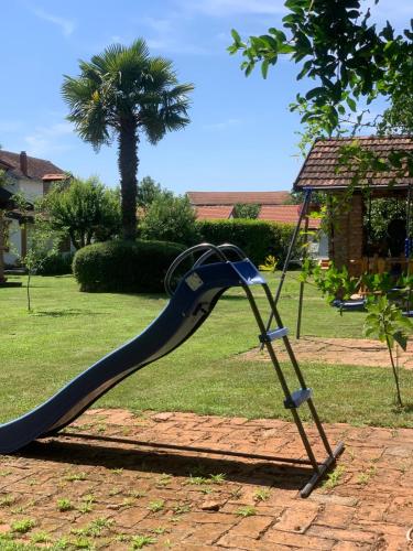 a playground slide in a yard with a palm tree at Ranc Vitina in Ljubuški