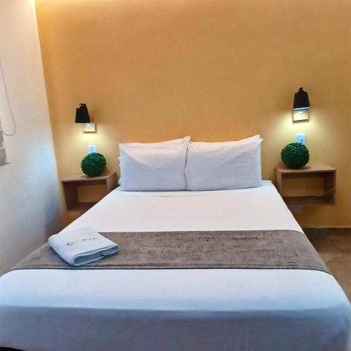 a bedroom with a bed with a book on it at Hotel Cabo de la Vela Medellin in Medellín