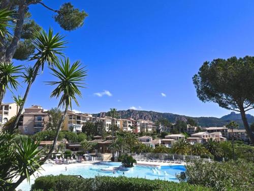 a resort swimming pool with palm trees and buildings at Dans un cadre d'exception, Vue mer panoramique à Agay Côte d'Azur, Village Vacances Cap Esterel, 2 chambres, avec jardin, golf, climatisation, Wifi, 5 piscines in Agay - Saint Raphael