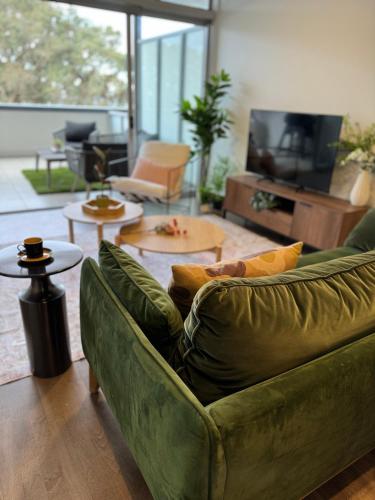 a living room with a green couch and tables at Beach Front Dream Lifestyle in Auckland