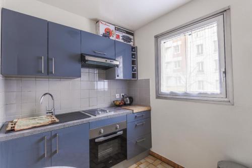 une cuisine avec des placards bleus et une fenêtre dans l'établissement Cosy family flat, à Clichy