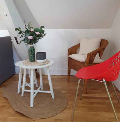 une table, une chaise et un vase avec des fleurs dans l'établissement Quiétude au Bord de Loire., à Orléans