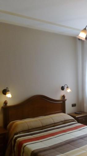 a bedroom with a bed with two lights on the wall at Hostal Granada in Salamanca
