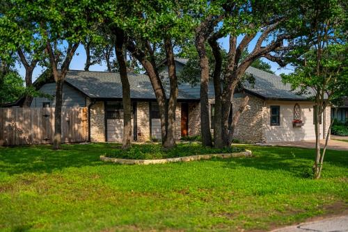 a brick house with trees in a yard at Serene Family Retreat King Beds Pool Hot Tub and Games in Cedar Park