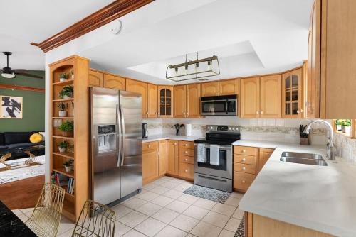 a kitchen with wooden cabinets and a stainless steel refrigerator at Serene Family Retreat King Beds Pool Hot Tub and Games in Cedar Park