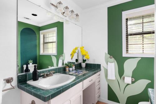 a bathroom with a sink and a green wall at Serene Family Retreat King Beds Pool Hot Tub and Games in Cedar Park
