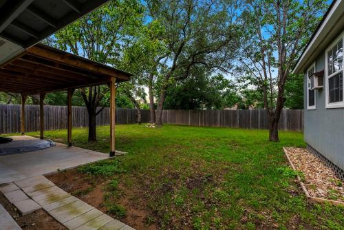 a backyard with a wooden pergola and a fence at Serene Family Retreat King Beds Pool Hot Tub and Games in Cedar Park