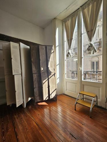 an empty room with a chair and two windows at BA Stop Hotel House in Buenos Aires