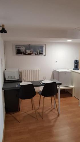 une cuisine avec une table noire et deux chaises dans l'établissement Studio meublé en sous-sol en plein centre ville, à La Ferté-Bernard