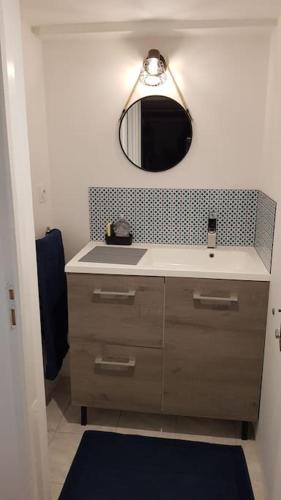 une salle de bain avec un lavabo et un miroir dans l'établissement Studio meublé en sous-sol en plein centre ville, à La Ferté-Bernard