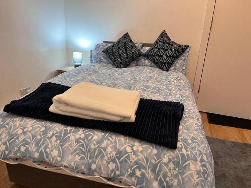 a bed with black and white pillows on it at HIVESTAYS Free Wi-Fi, Smart TV, Parking, Tea &Coffee in Kettering