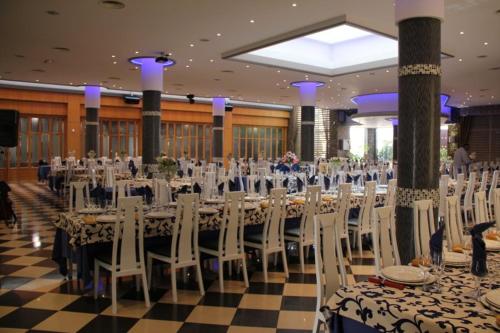 a banquet hall with long tables and white chairs at Hotel Frijon in Aceuchal