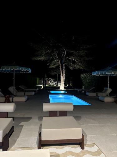 - une piscine avec chaises longues et parasols la nuit dans l'établissement Villa & Maison d'exception Deauv Hills, Deauville, à Bonneville-sur-Touques