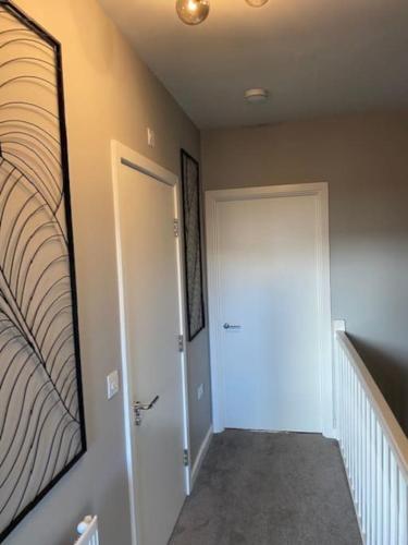 a hallway with a white door and a mirror at Modern house by the canal in Southall