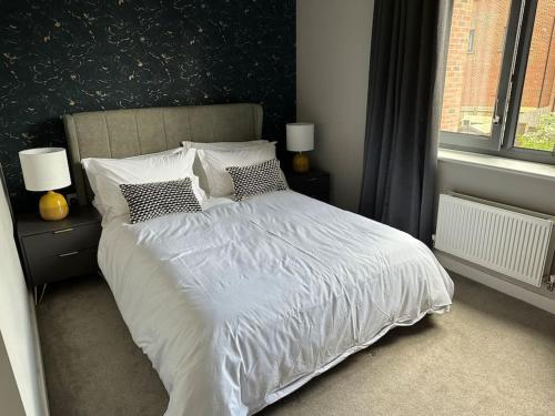 a bedroom with a white bed with pillows and a window at Modern house by the canal in Southall