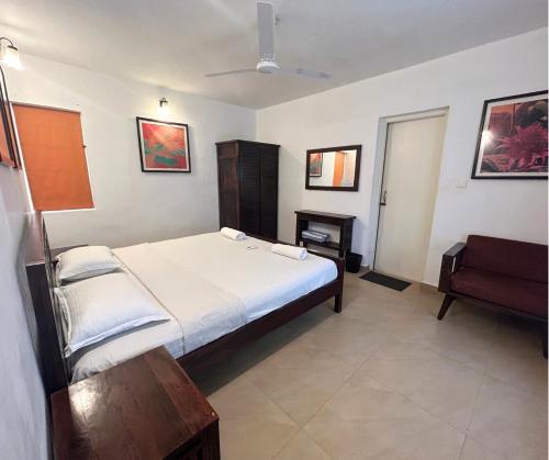 a bedroom with a large bed and a chair at Jungle Hut-Annabelle's Beach Apartments at Bernard Simao,Calangute,Goa in Candolim