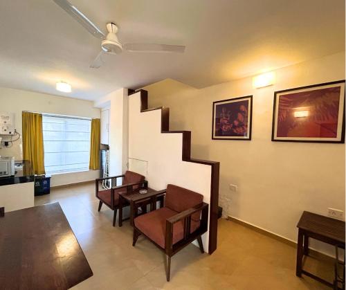 a living room with a staircase and a table and chairs at Jungle Hut-Annabelle's Beach Apartments at Bernard Simao,Calangute,Goa in Candolim