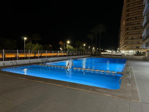 a large blue swimming pool at night with lights at Apto. Cullera vistas espectaculares primera línea in Cullera