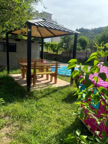 a wooden picnic table under a gazebo next to a pool at taisya guest house in Borjomi