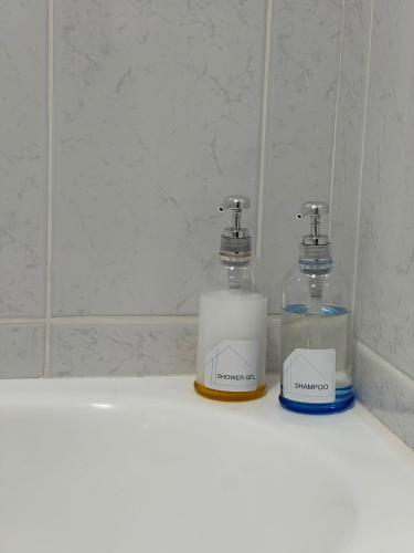 two glass bottles sitting on a counter in a bathroom at Guest House MJ in Póvoa de Varzim