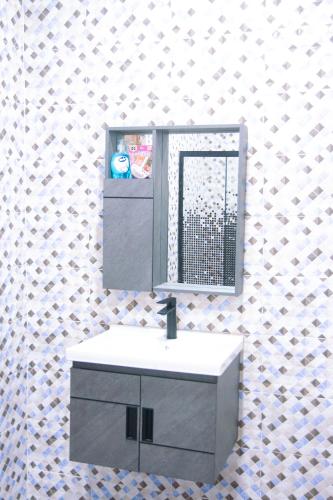 a bathroom with a sink and a mirror on a wall at Adji's Cozy Villa in Apenkwa