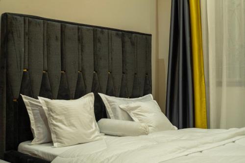 a bed with a black headboard and white pillows at Joshean Apartments in Wakiso
