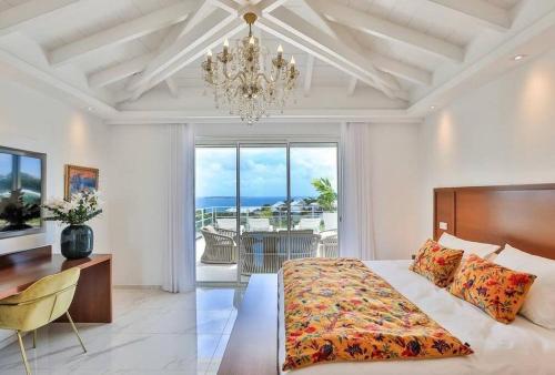 Un dormitorio con una cama, un escritorio y una lámpara de araña. en Villa Fleurs de Lys, en Orient Bay