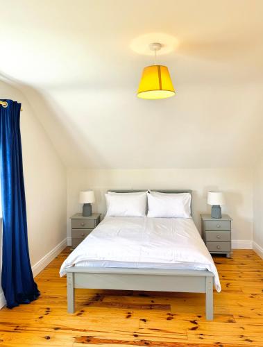 a bedroom with a white bed and blue curtains at No's 6, 8 & 9 Dingle Lispole Holiday Homes in Lispole