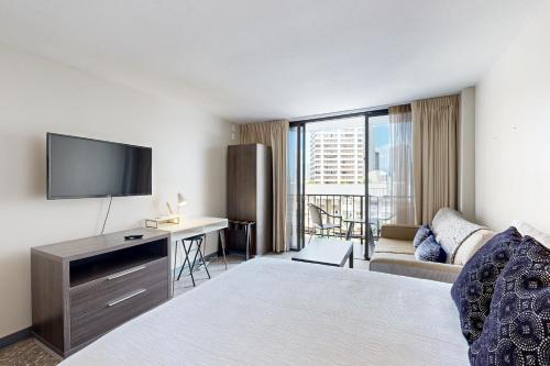 a hotel room with a bed and a flat screen tv at Palms at Waikiki #311 in Honolulu
