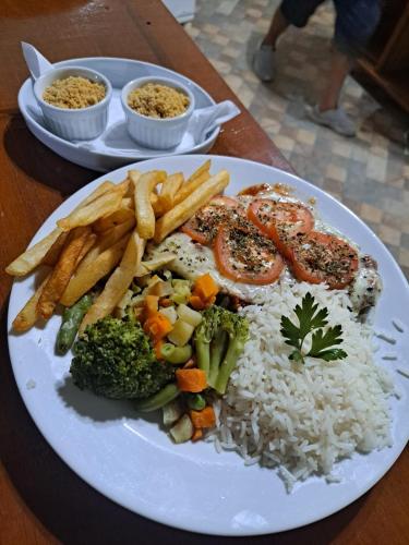 a plate of food with rice and vegetables and french fries at Pousada Vale da Serra in Serra Negra