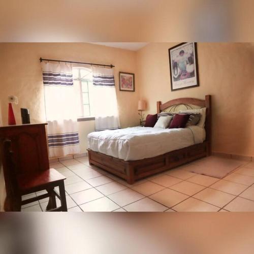 a bedroom with a bed and a chair and a window at La casa de la tía 3B Cuernavaca in Acapantzingo